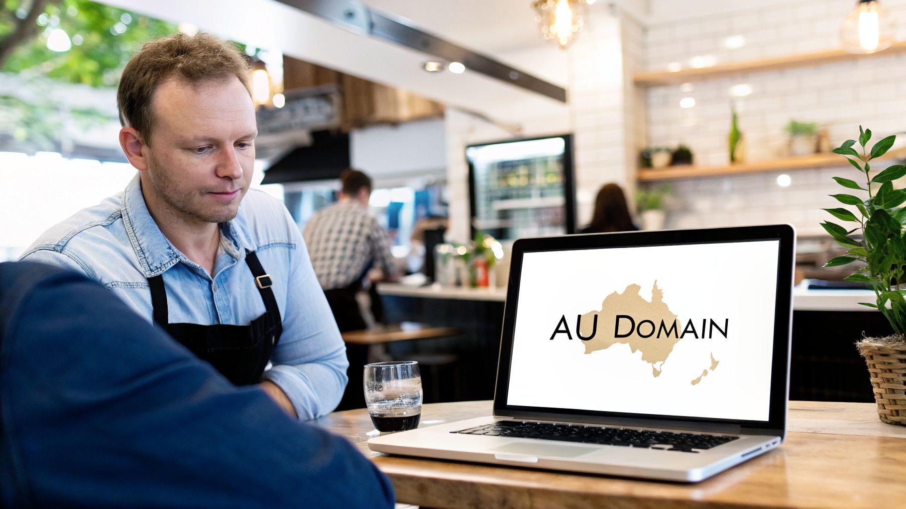 Man in cafe looking at laptop displaying AU Domain Australia map, discussing business.