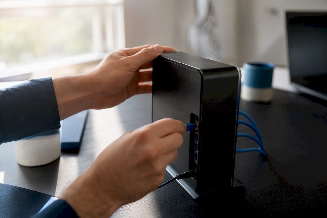 Hands plugging ethernet cable into router